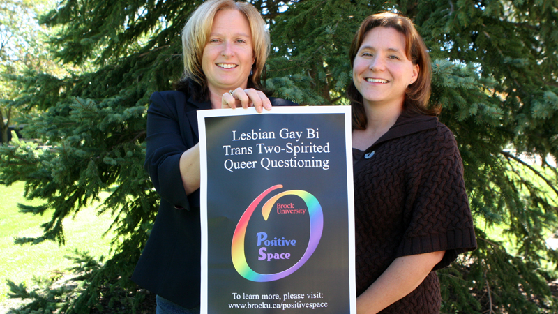 Lynne Prout and Marla Portfilio display a Positive Space poster.