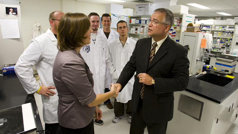 Gary Goodyear, right, shakes hands with graduate student Ellen Robb as graduate students give him a tour of a Brock lab.