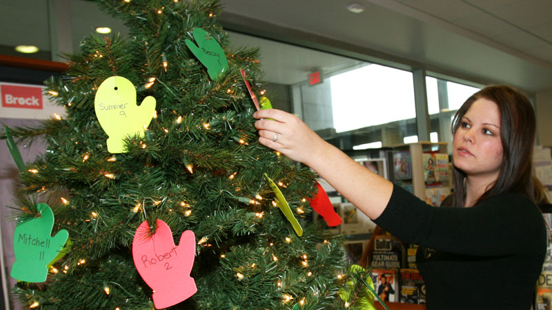 Kamila Dziuran, third-year student and cashier at the Campus Store, examines the Adopt and Angel tree.