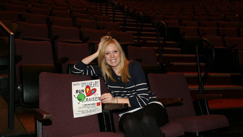 Emma Bulpin poses with a Both Sides of the Heart poster.