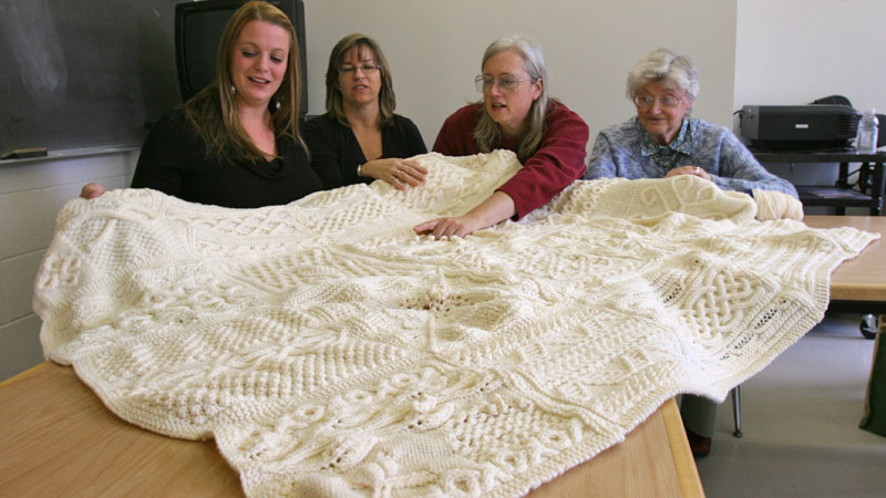 Brock's knitting group has made an afghan to raffle off for the United Way. With the afghan, from left, are Koreen McCullough from ESL Services; Marianne Vessel, budget officer for the Faculty of Business; Jo Stewart, administrative officer in the Faculty of Social Sciences, and Barbara Bucknall, a French professor who retired in 1993.