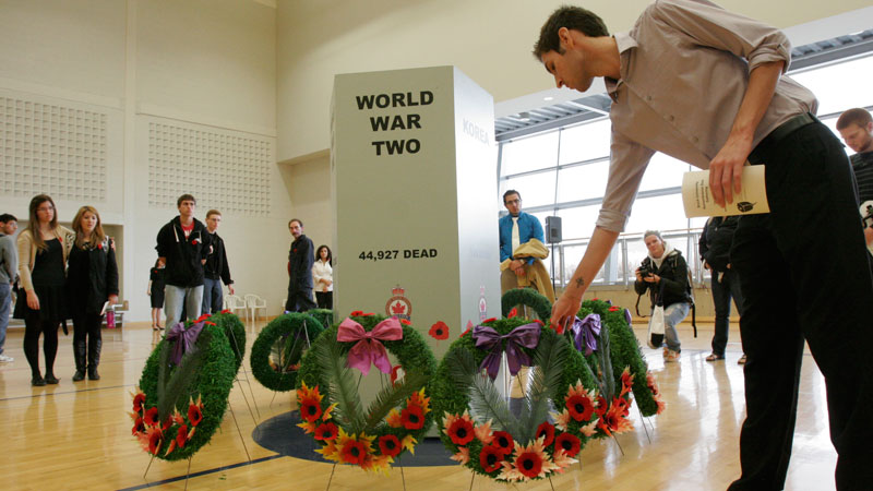 Staff and students pin poppies to the wreaths laid in the Ian Beddis Gym.