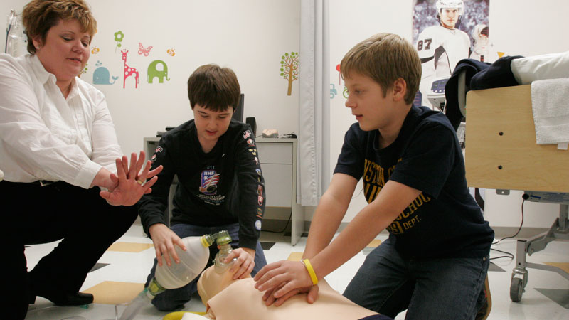 John Arseneau, centre, and Ross Horsley, right, learn chest compressions and administering oxygen as Elizabeth Horsley gives instructions.