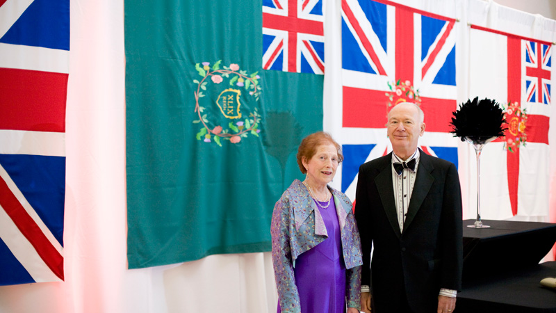 Marilyn I. Walker and Norris Walker stand in front of the regimental colours at General Brock's October Soiree.