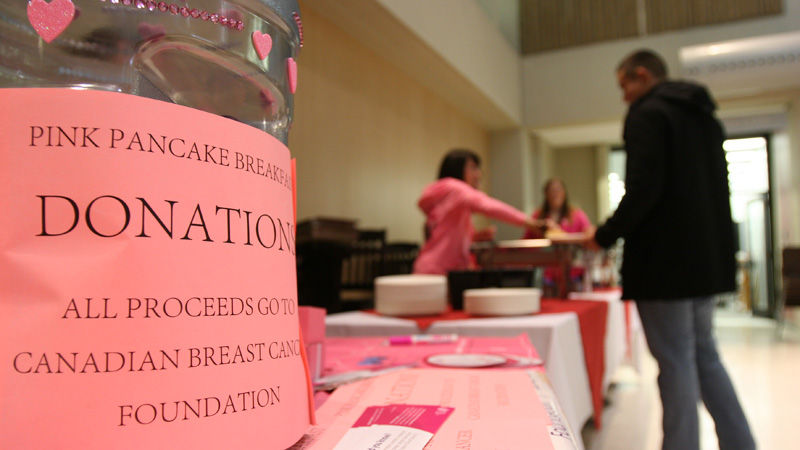Student Life and Community Experience workers dish out pancakes to raise money for breast cancer research.