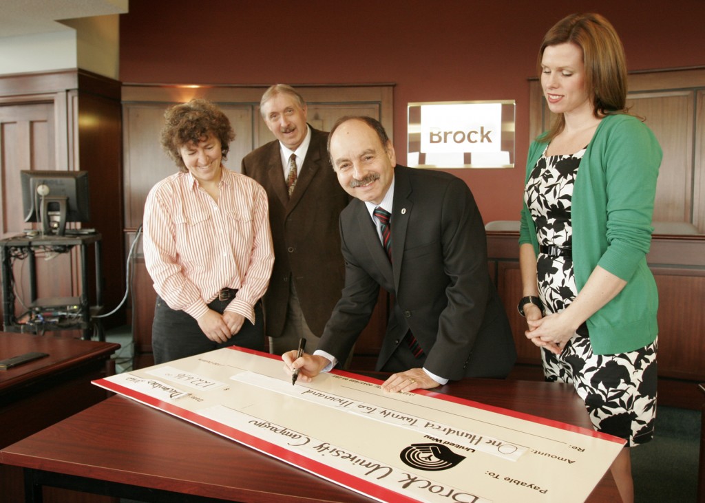 Brock President Jack Lightstone fills out the ceremonial cheque for the United Way after the University surpassed its campaign goal for the charity. With him are Lucie Thibault (far left) and Mike Plyley, the campiagn's faculty co-chairs, and campaign chair Diana Panter.