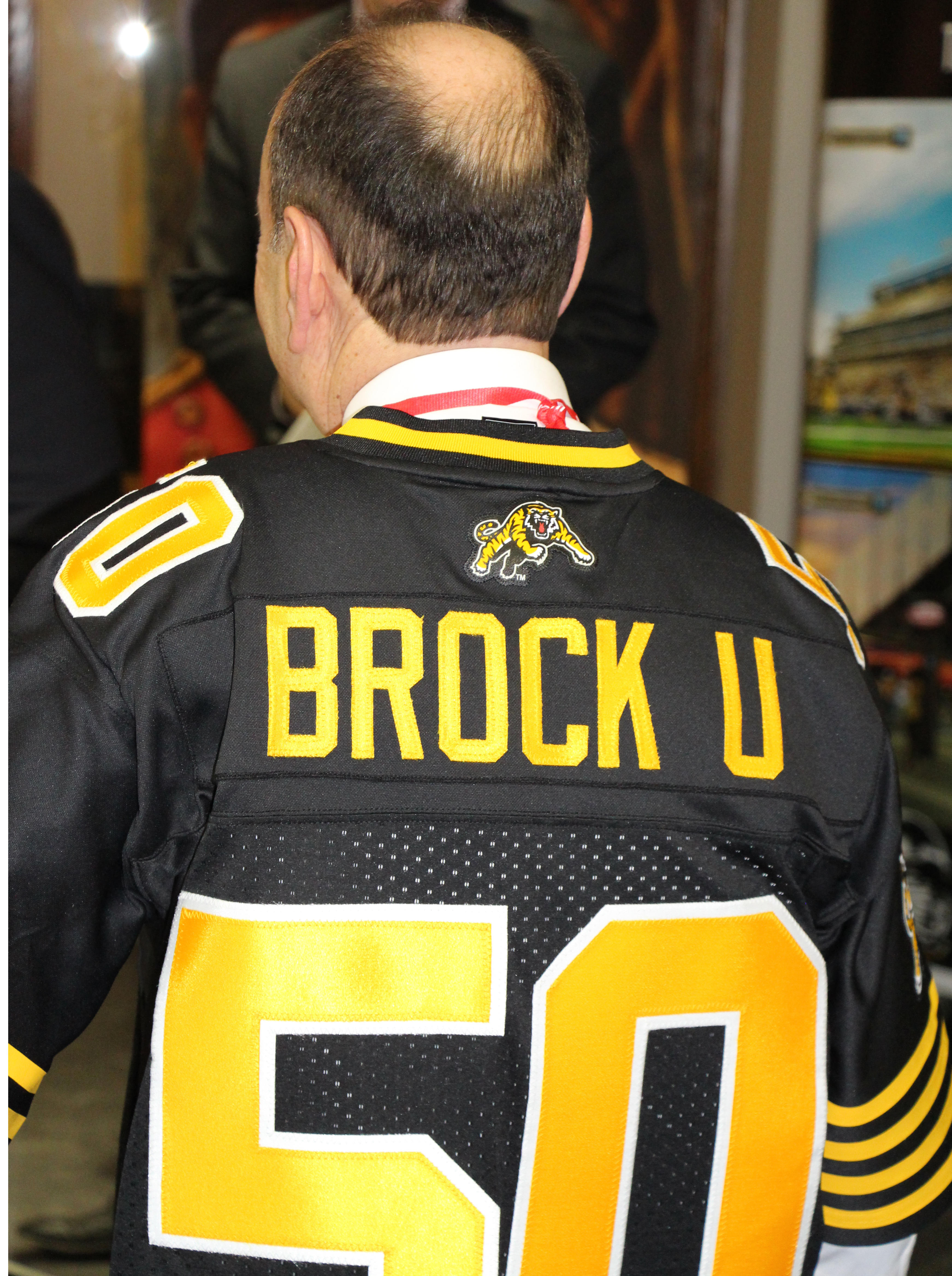 Brock President Jack Lightstone wears a #50 Hamilton Tiger-Cats jersey.