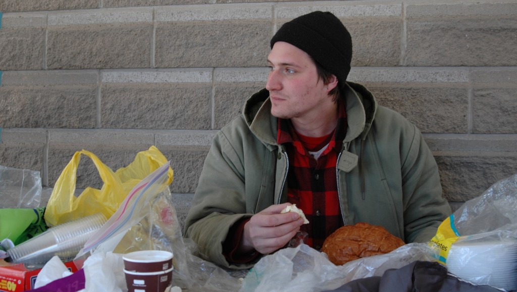 Caleb Regier eats cheese and bread that was given to him during the 5 Days for the Homeless campaign happening outside Taro Hall.