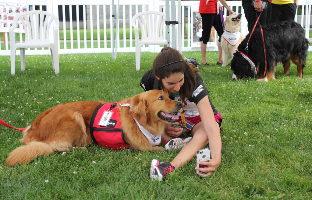 An athlete from Mexico snaps a selfie with a therapy dog Monday in Jubilee Court.