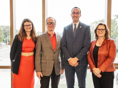 A group of 4 people in business attire pose for a photo in front of a large window. From left to right: Meaghan Rusnell, Interim Vice-President, External, Brock University; Mark Arthur, Chair of Brock University's Board of Trustees; the Honourable Nolan Quinn, Ontario Minister of Colleges and Universities; and Lesley Rigg, President and Vice-Chancellor, Brock University.