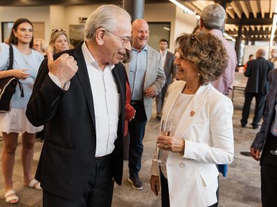 A man and a woman wearing business attire smile in conversation.