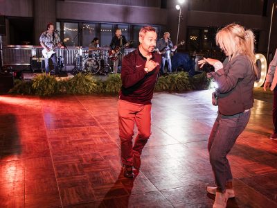 Guests dance on a dance floor as a band plays in the background.