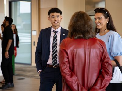 Three people stand in conversation, one with their back to the camera.