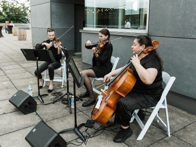 A string trio plays music at an outdoor event.