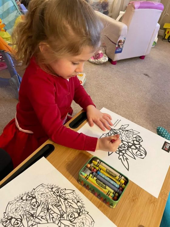 Young girl colouring at table for Valentine's Day