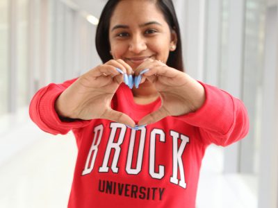 Brock student making a heart sign at the camera with her hands.
