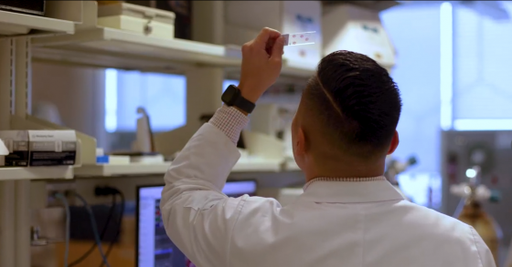 Dr. Val Fajardo holding up slide in laboratory