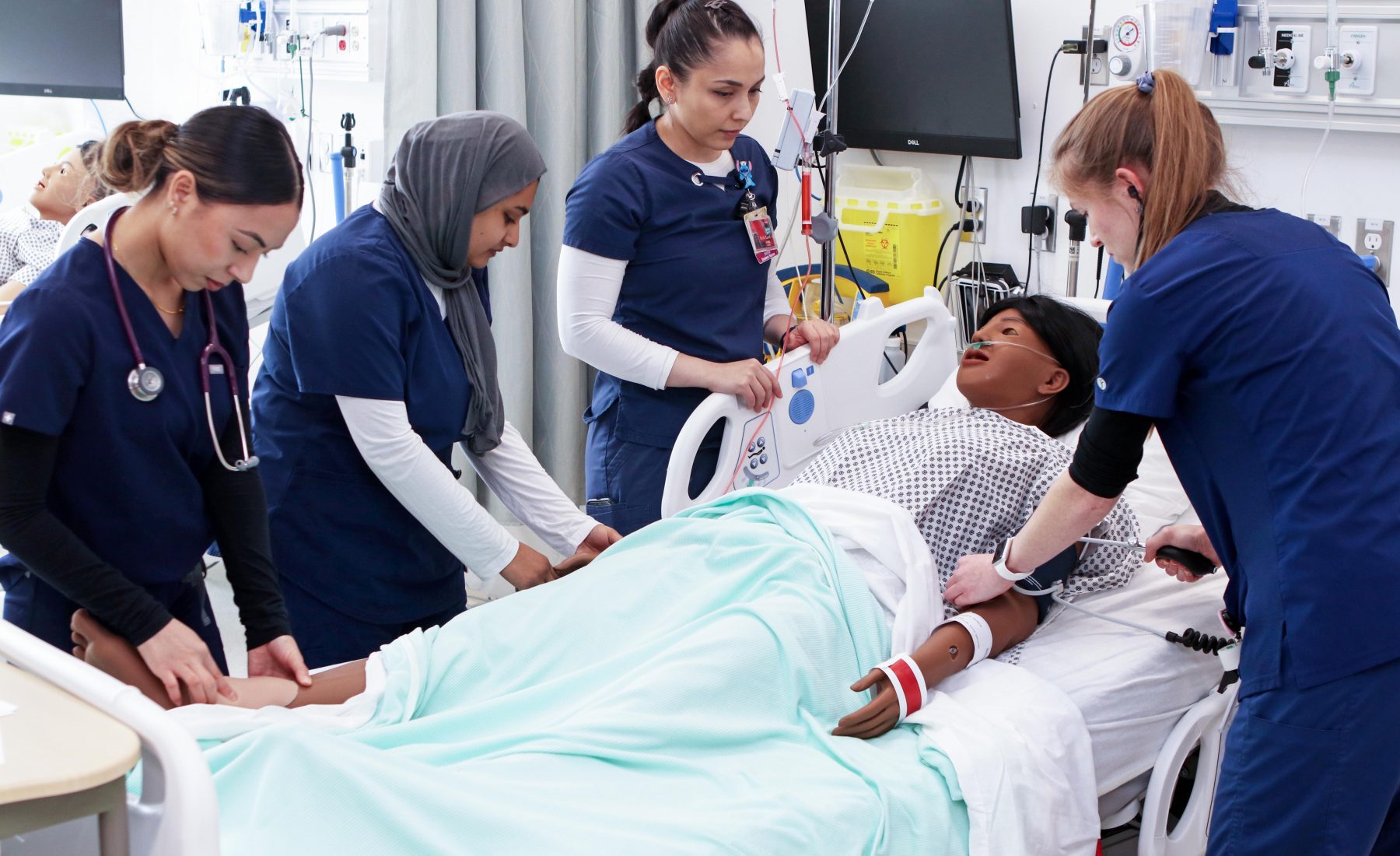 Nursing students gather round a patient simulator 