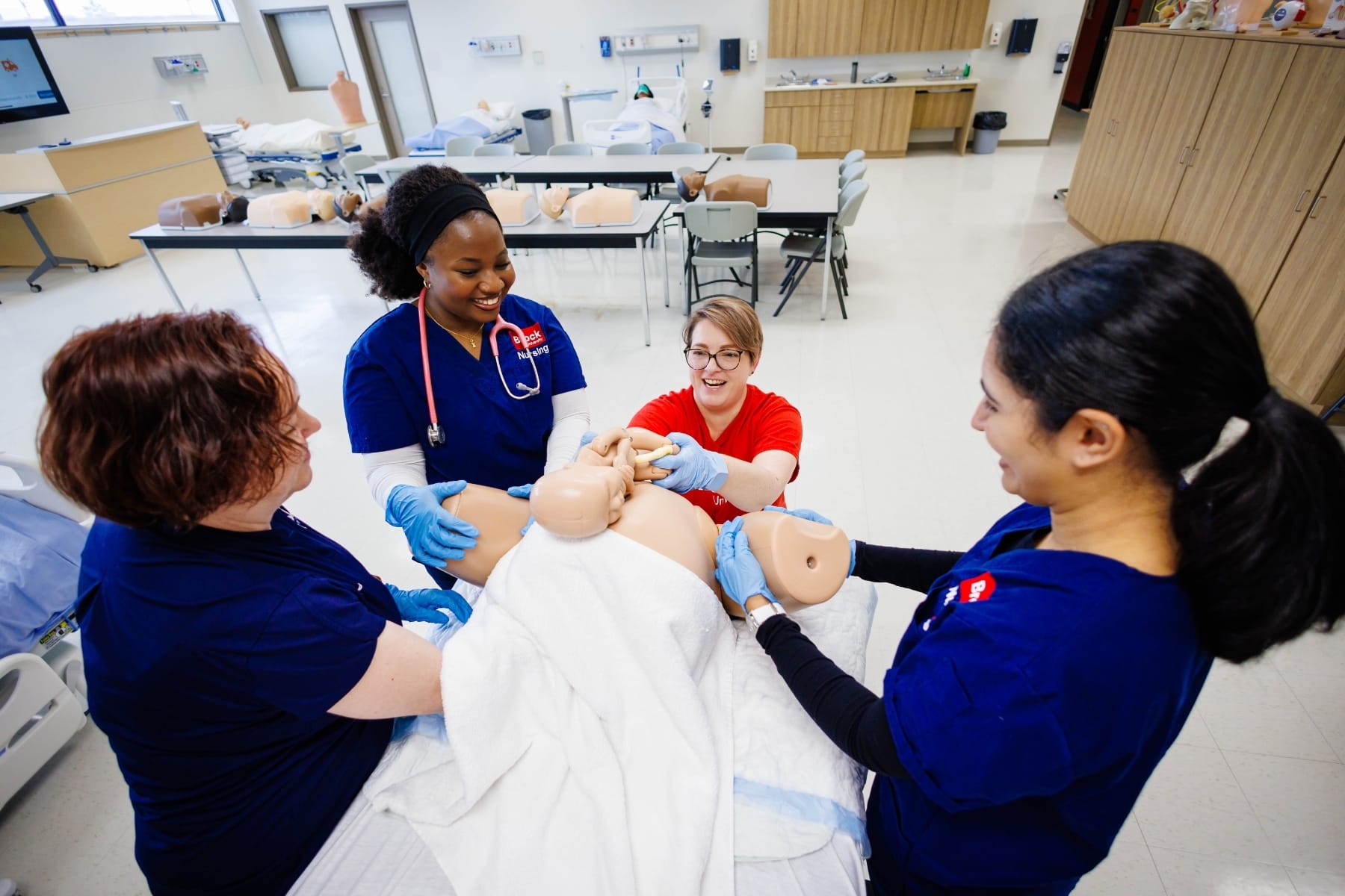 Nursing students with professor evaluating a Medical baby doll
