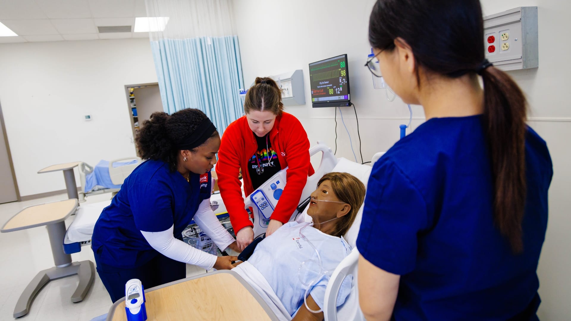 nursing students and teacher applying pressure cuff to a simulated patient