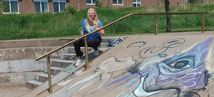 Brock student sits on steps outside long term care home and beside skateboard park