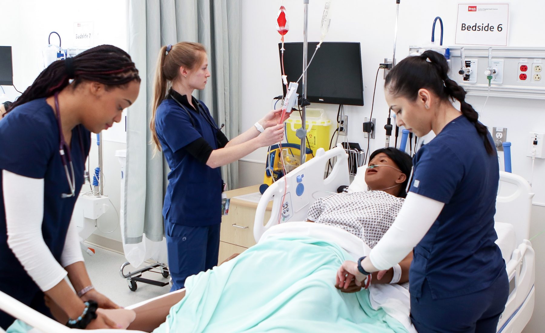 Three Brock University Nursing students assess a high-fidelity patient simulator 