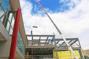 Construction workers work to install the final beam to the framework of the Goodman School of Business building.