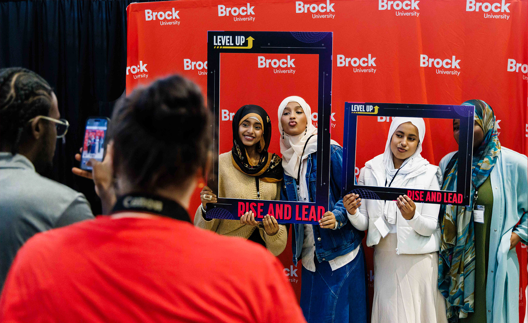 Example of students using a Brock branded backdrop to take photos at a conference.