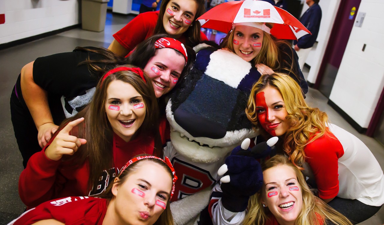Brock University students pose with Boomer the Badger before a hockey game during the 2014 Steel Blade Tournament.