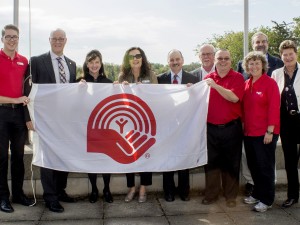 A group of people hold a United Way flag outdoors.