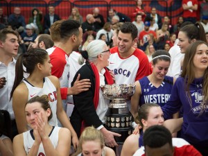 Basketball players celebrate with Brock's Assistant Athletic Director Chris Critelli after the OUA women's basketball trophy was named the Critelli Cup in her honour.