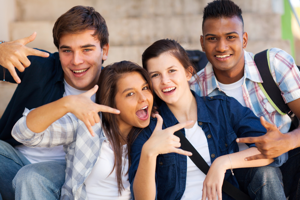 group of happy teenagers giving cool hand signs