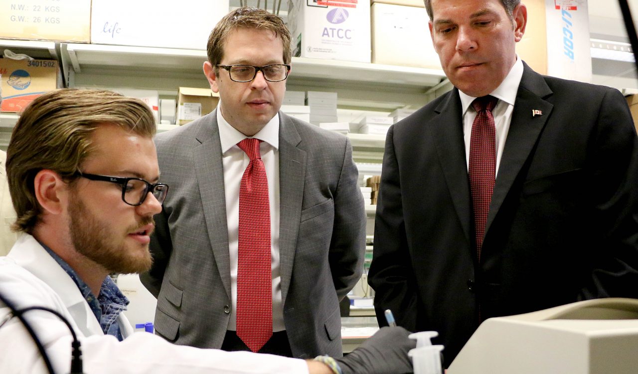 Brock University student Aindriu Maguire, an NSERC Undergraduate Student Research Awardee, explains cell research to Members of Parliament Vance Badawey (Niagara Centre), right, and Chris Bittle (St. Catharines) in the lab of Assistant Professor of Health Sciences Adam MacNeil during a tour at Brock University Tuesday, June 28.