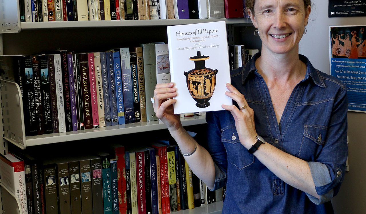 Classics Professor Allison Glazebrook holds a copy of her new book Houses of Ill Repute: The Archaeology of Brothels, Houses, and Taverns in the Greek World.
