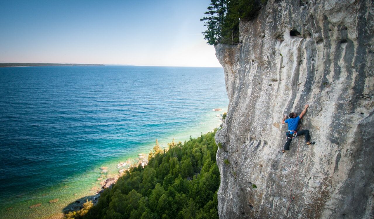 Aaron Brouwers climbing on a rock face near a lake