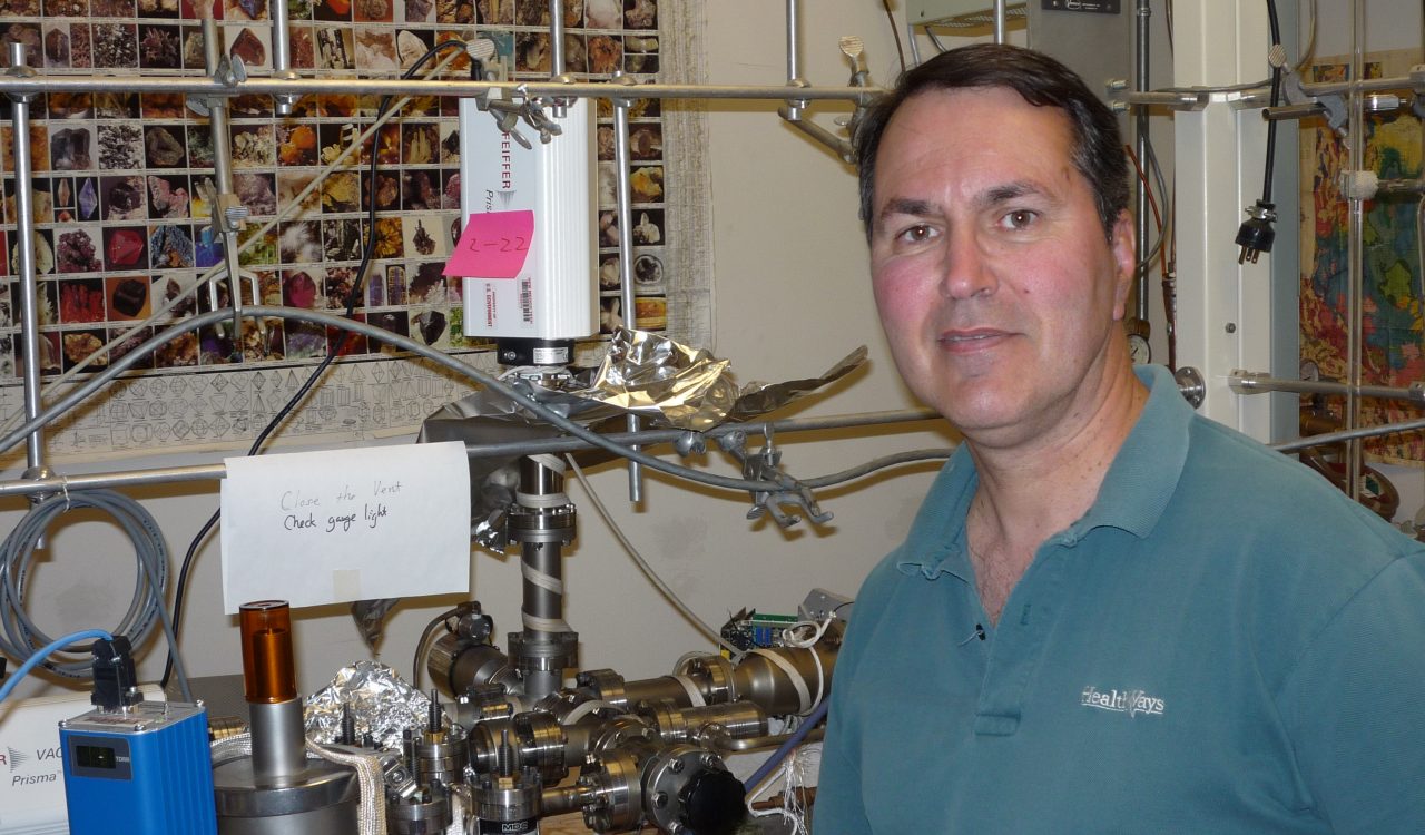 Earth Sciences Professor Nigel Blamey in front of a machine built to measure oxygen in prehistoric air.