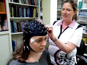 Psychology Professor Kimberly Cote attaches a sleep monitor to grad student Kari Lustig.