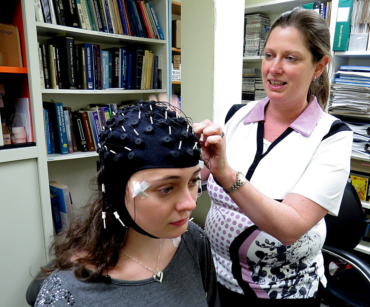 Psychology Professor Kimberly Cote attaches a sleep monitor to grad student Kari Lustig.