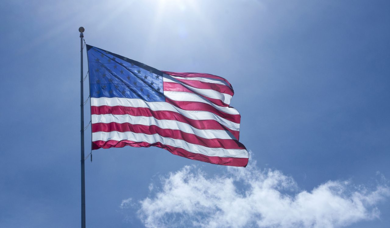 A waving U.S. Flag is back-lit in the afternoon sun.