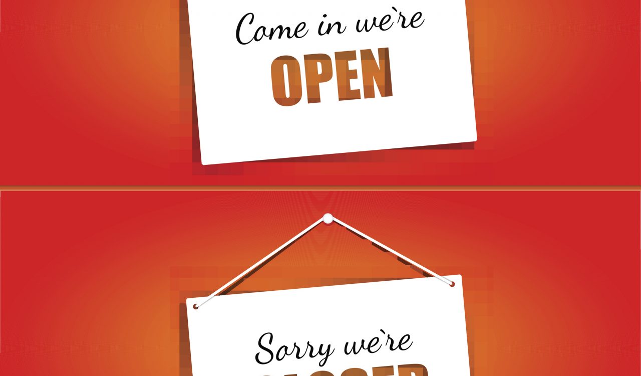 Open and closed signs in red letters on white hanging signs against a red background