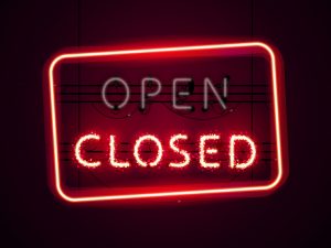 A red neon sign illuminates the word closed, while the word open is not illuminated.