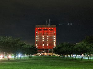 A large square building illuminated with red lights..