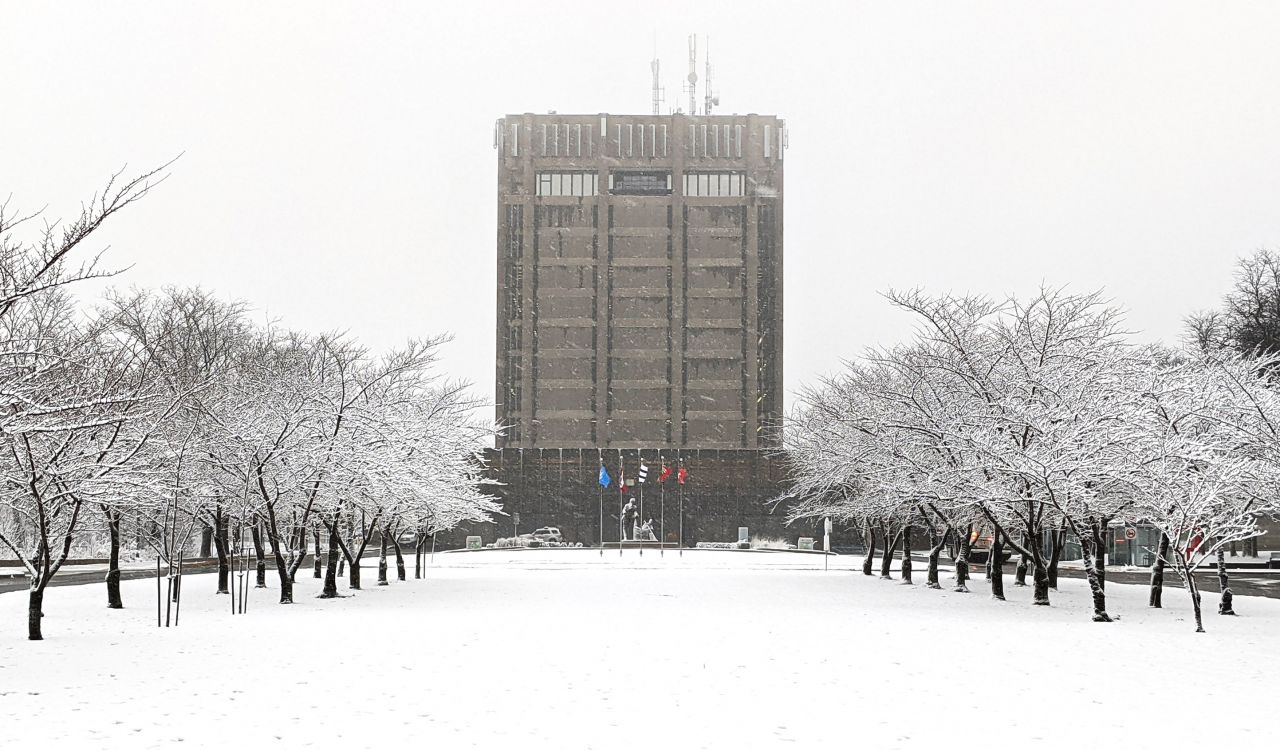 A snowy lawn in front of a square building