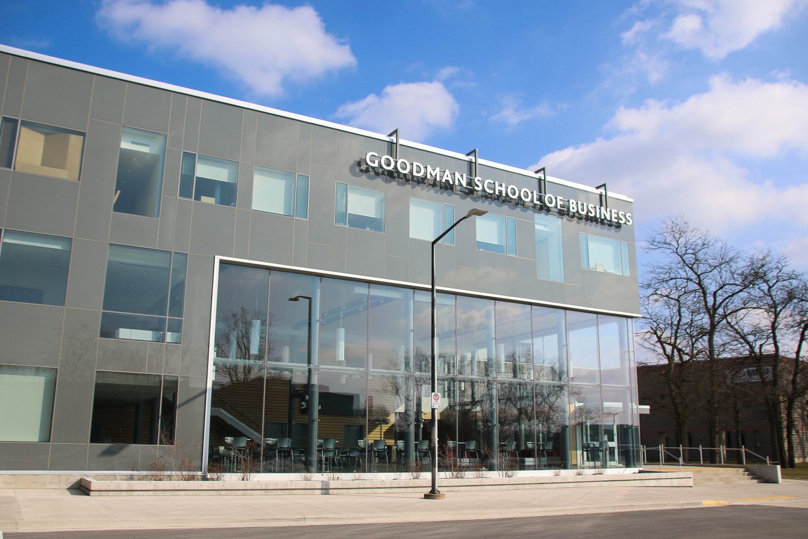 A grey and glass building is pictured with the words Goodman School of Business across the top.