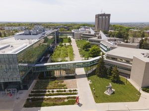 An aerial photo of Brock’s main campus with the Mackenzie Chown complex on the right, the Roy and Lois Cairns Health and Bioscience Research Complex on the left and the Schmon Tower in the distance.