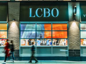 The exterior of an LCBO store with customers and staff visible through the windows.