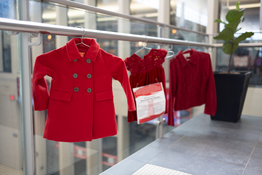 Red coats and dresses hang on a rail inside Brock University