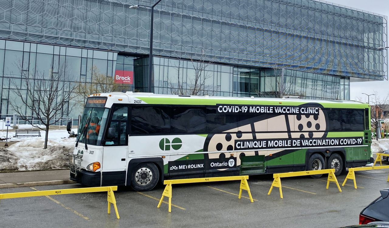 A large green bus that serves as a mobile vaccination clinic.