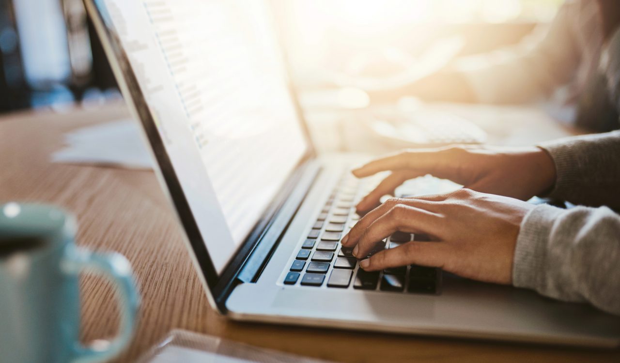 A person’s hands typing on a laptop computer.