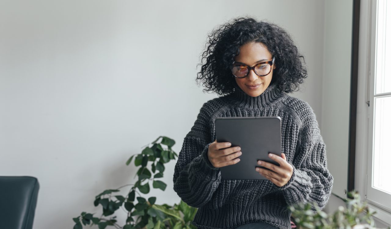 Young woman wearing glasses watching something on her digital tablet